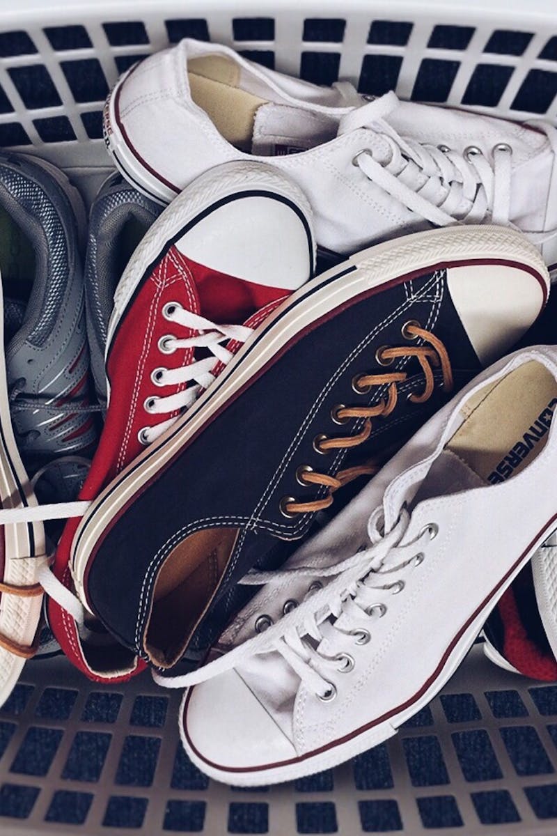A variety of vintage sneakers piled in a white laundry basket. Perfect mix of style and nostalgia.