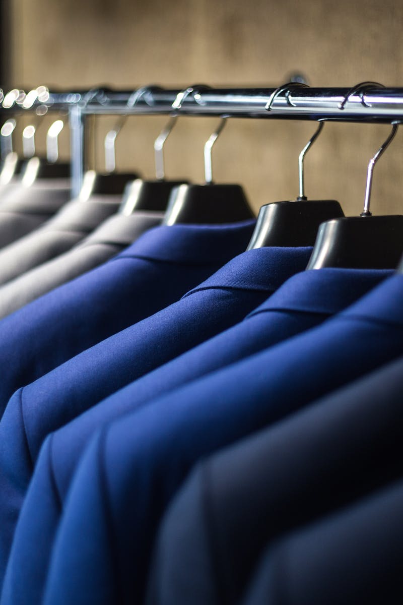 Close-up of neatly arranged suits in a wardrobe, showcasing fashion and organization.